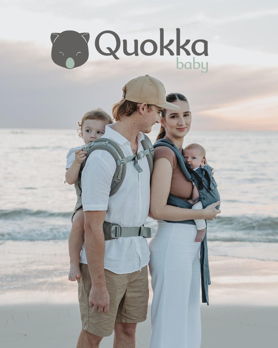 pap&aacute;s porteando en la playa en la espalda y delante en portabeb&eacute;s ergon&oacute;micos Quokkababy